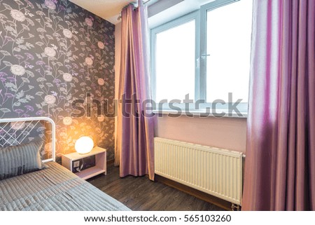 Interior bedroom with a large double bed with bedside tables, window on a background of modern wallpaper