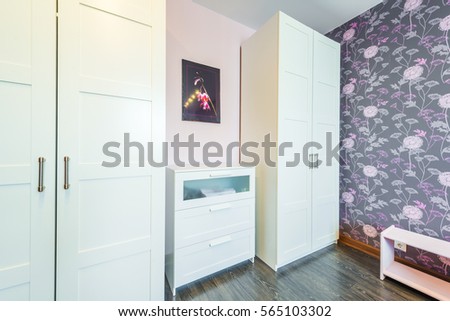 Interior bedrooms with wardrobes, chest of drawers, bedside table against the background of modern wallpaper