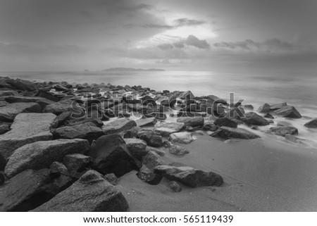 Waves, rocks and beach in Marang, Terengganu, Malaysia in long exposure, in black and white. Soft focus due to long exposure.