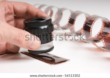hand holding a magnifying glass and twisted film