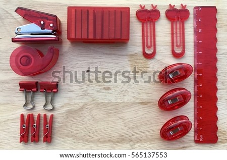 A set of red  office stationery supplies on wooden background clips ruler stapler filling stapler paper-clip clear adhesive tape