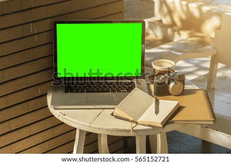 Mockup image of laptop with blank green screen on wooden table