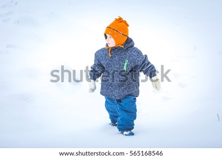 Happy boy playing outdoor in winter. Caucasian child in orange hat and warm clothes playing outdoor in winter.