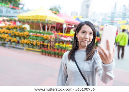 Woman taking selfie by mobile phone in flower market