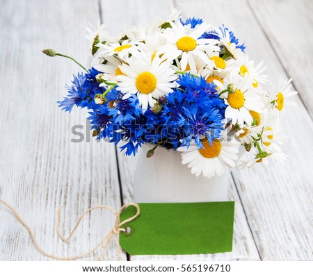 daisies and cornflowers  in vase on a old wooden table