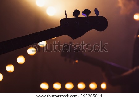 Live music background, electric bass and solo guitar silhouettes, closeup photo with soft selective focus