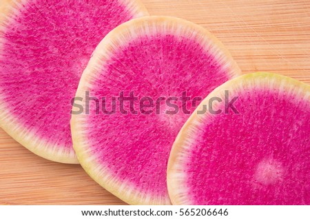 Background texture of several slices of watermelon radish. Watermelon Radish on a wooden surface. Daikon purple radish vegetable on bamboo cutting board close-up. Space for your text. Top view