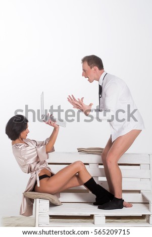 young couple of handsome amazed man or businessman and pretty woman or girl working on portable laptop or computer in shirt, socks and tie, sits on wooden bench isolated on white background