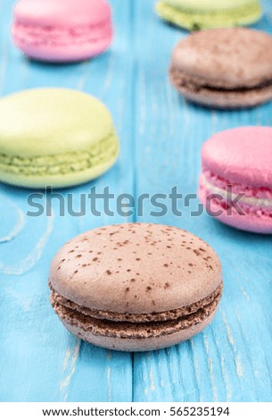 Multicolored macaroon scattered on a wooden background close up