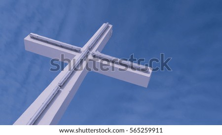 White cross with bright blue sky and clouds in background