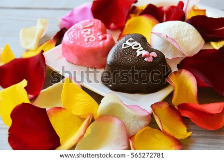 two cakes in the shape of hearts and colorful rose petals
