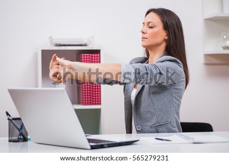 Young businesswoman is relaxing in her office. She is stretching her body. Royalty-Free Stock Photo #565279231