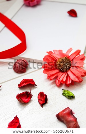 Top view of red dry petal, ribbon, flower and white picture frame for your text for a love Valentine`s day on wooden background. Flat lay.