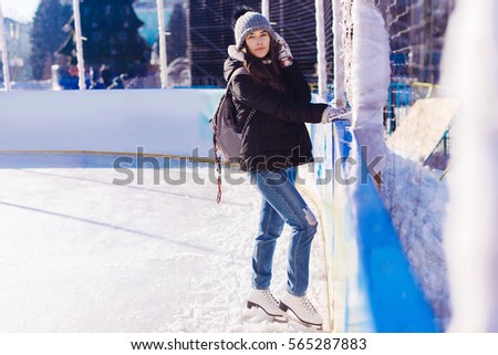 Young and pretty girl skating on outdoor open air ice-rink at winter.