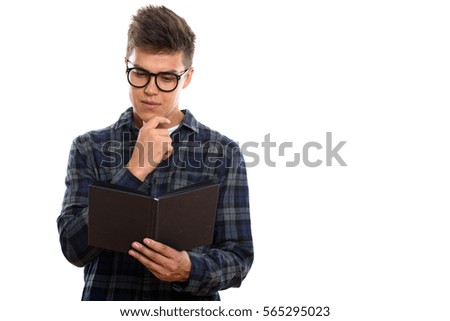 Studio shot of young handsome man reading book while thinking