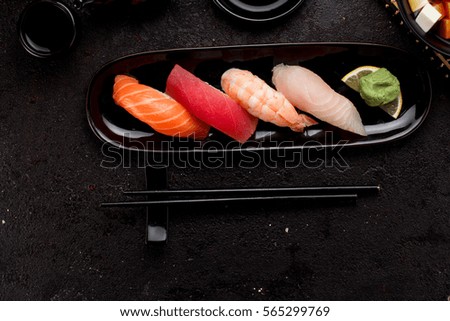 Sushi set on a black plate and miso soup over dark concrete background