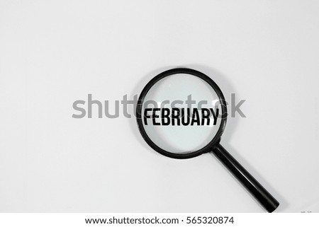 A concept image of a magnifying glass isolated white background with a word FEBRUARY zoom inside the glass 