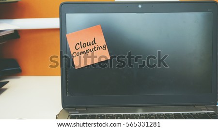 A Technology concept image of a laptop with black screen on an office desk with a red sticky note contain word Cloud Computing