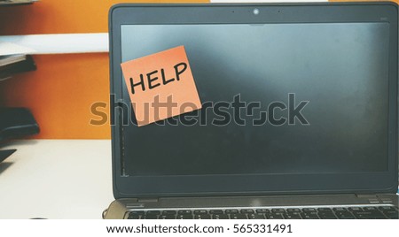 A Technology concept image of a laptop with black screen on an office desk with a red sticky note contain word HELP