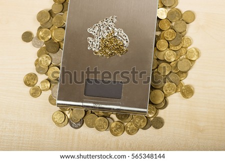 Digital scale and some gold coins. Silver and gold necklaces. At the jewelers. Pawn shop. Silver and gold on the table.