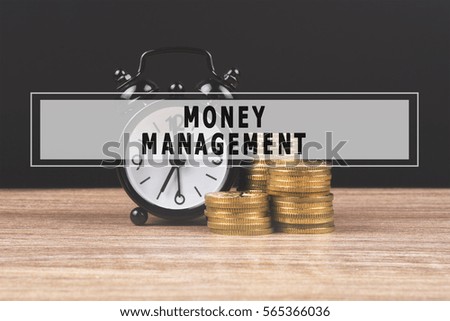 Alarm clock and money coin stack on wooden table and black background with text MONEY MANAGEMENT. Finance concept, copy space.