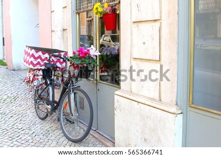 Bike and artistic style decorations, flowers in basket and colorful cycle bags in street with old buildings, Lisbon, Portugal