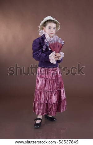 The little girl with a fan in a hand, on a grey background looks at you, focusing on eyes