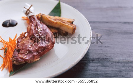 Duck leg on an Asian. a dish of pan-Asian cuisine on a white plate with dark backgrounds