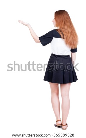 Back view of Beautiful woman in dress looking at wall and Holds  hand up.  young redhead girl standing. Rear view people. Isolated over white background. 