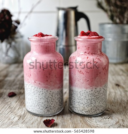 Sweet pinky breakfast in the bottles. Overnight chia seed vanilla pudding and grilled black sesame. Topped with  raspberries smoothie.  Royalty-Free Stock Photo #565428598