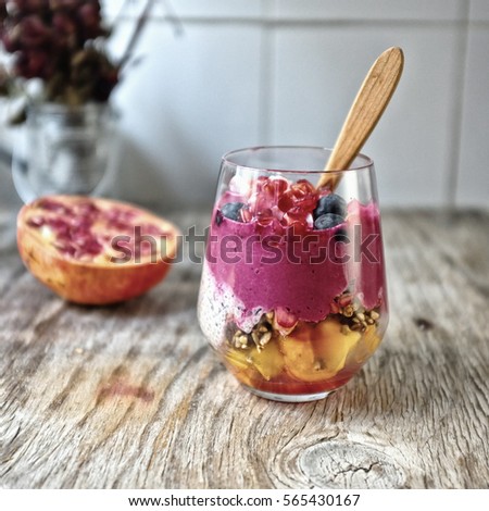 Overnight vanilla chia seeds pudding in almond milk and black sesame and beetroot dates smoothie, with fresh papaya, raw granola grains and seeds, dates, coconut crated, pomegranate and blueberries. Royalty-Free Stock Photo #565430167