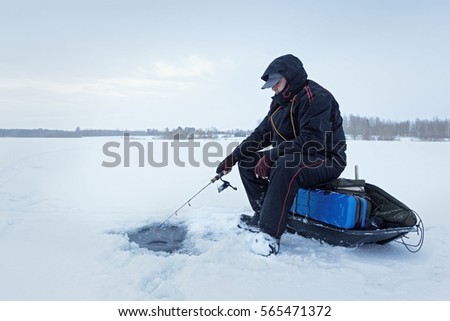 Ice fishing. Fisherman sitting on a frozen lake 