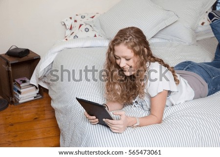 Teenager on bed, reading digital tablet
