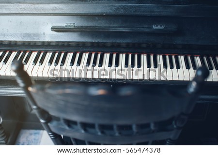 Black antique piano and a chair. General form