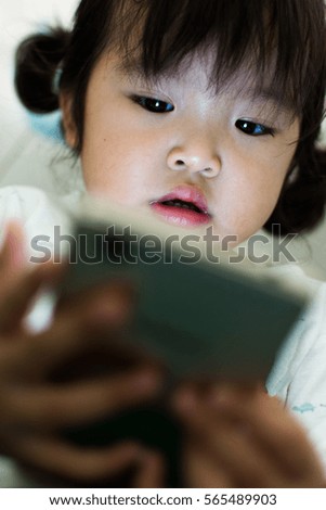 Little girl watching cartoon on mobile device.
