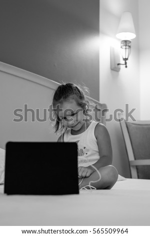Cute little girl watching cartoons on tablet at home