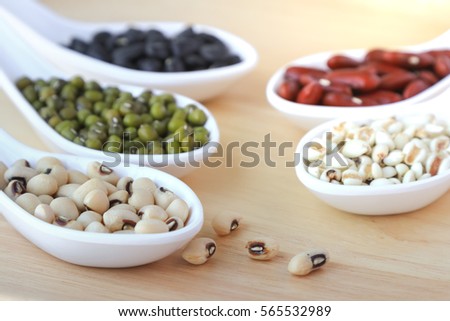 Assortment of beans and lentils in white spoon on wooden background. mung bean, groundnut, soybean, red kidney bean , black bean ,red bean and brown pinto beans . Healthy protein food.