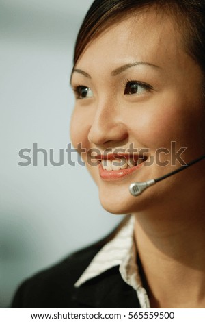 Young woman wearing hands-free device, looking away, smiling