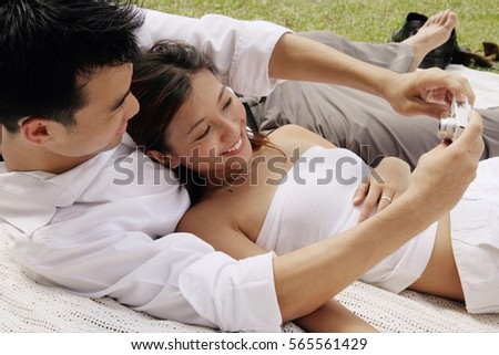 Couple lying on picnic blanket, taking a picture