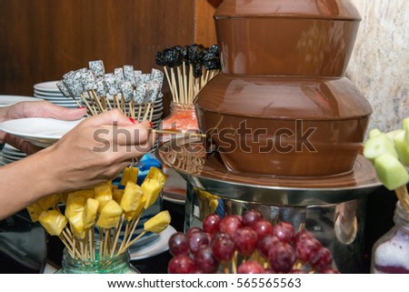 Chocolate fondue with fruits, hand with fondue, Food Buffet Catering,grapes,melon,dragon fruits,pineapple,banana,