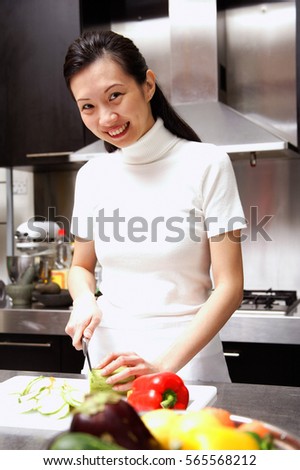 Woman cutting vegetables looking at camera, smiling
