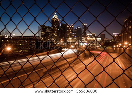 Night city skyline through the wire mesh fence. Abstract blurred cityscape background