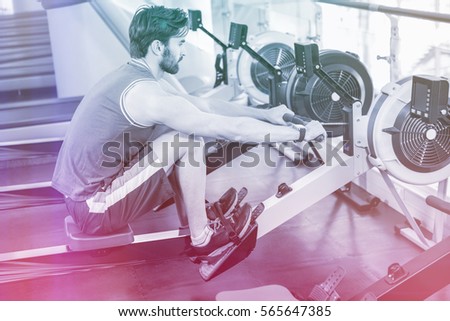 Handsome man doing exercise on drawing machine at gym