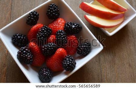 Flat lay of a bowl of mixed berries with a side of apple slices 