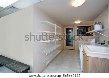 Basement Laundry room interior features white washer and dryer atop tiled floor and empty shelves  . Northwest, USA

