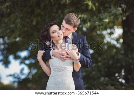 Bride and groom hugging in forest after beautiful wedding ceremony.