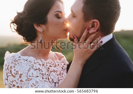 Beautiful bride and groom kissing in the mountains at sunset. Very beautiful white wedding dress designer. The man is a brunette with a beard.
Beautiful mountain nature