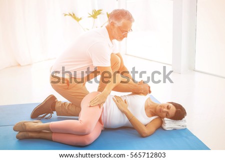 Doctor examining and giving physiotherapy to pregnant woman