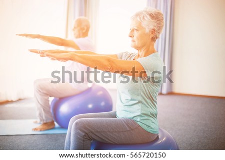 Seniors using exercise ball in studio