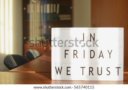 In Friday we trust sign in lightbox put on the desk in office interior.
